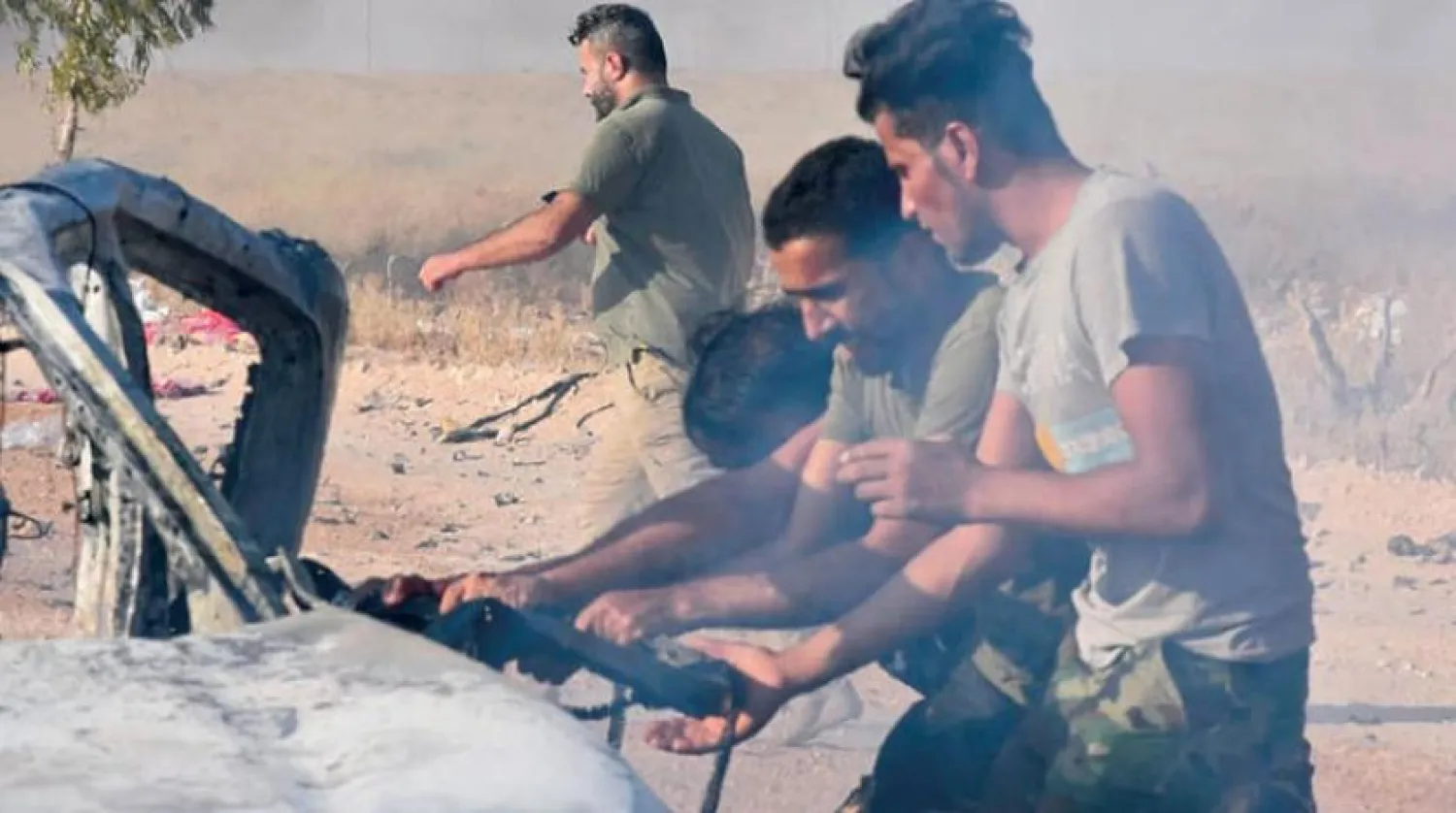 PMF members try to get a body out of a car after a drone attack near Qaim border crossing, in Anbar province, Iraq Sunday, Aug. 25, 2019. (AP Photo)