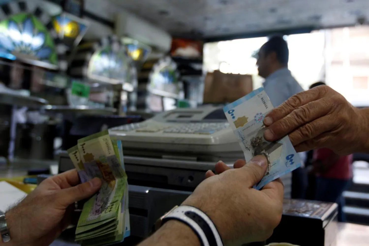 A cashier hands Syrian pounds to a customer inside a sweets shop in Damascus, Syria May 11, 2016. (Reuters)