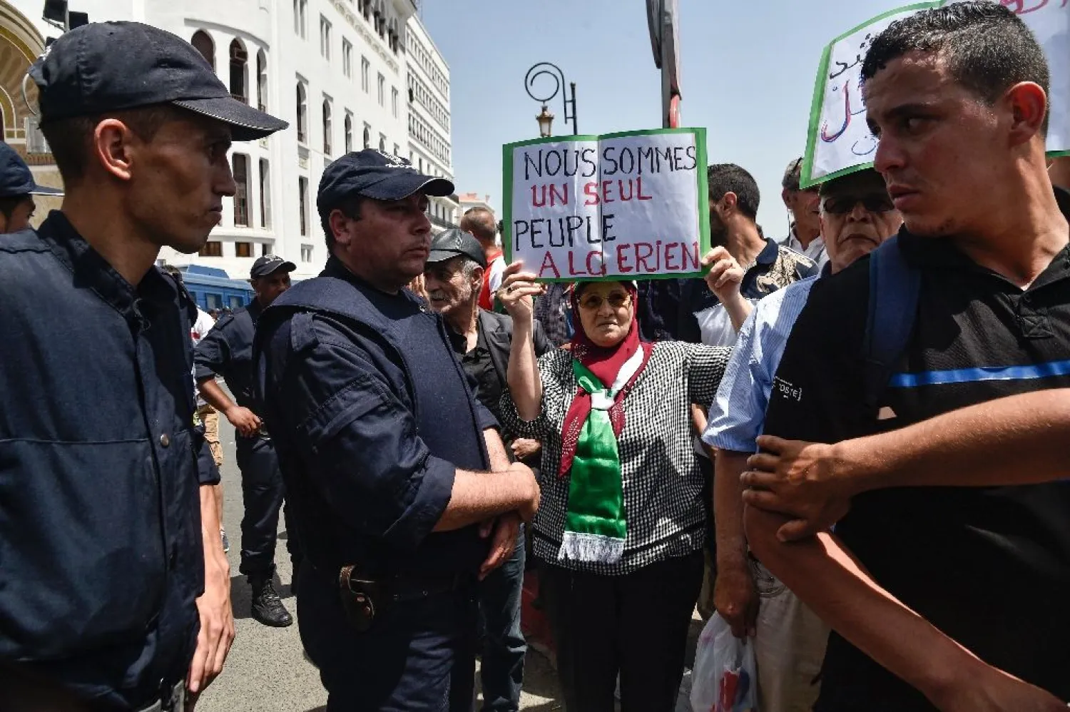 An Algerian woman wearing a scarf in the national colours holds up a sign reading in French "we are one Algerian people" on Friday (AFP Photo)
