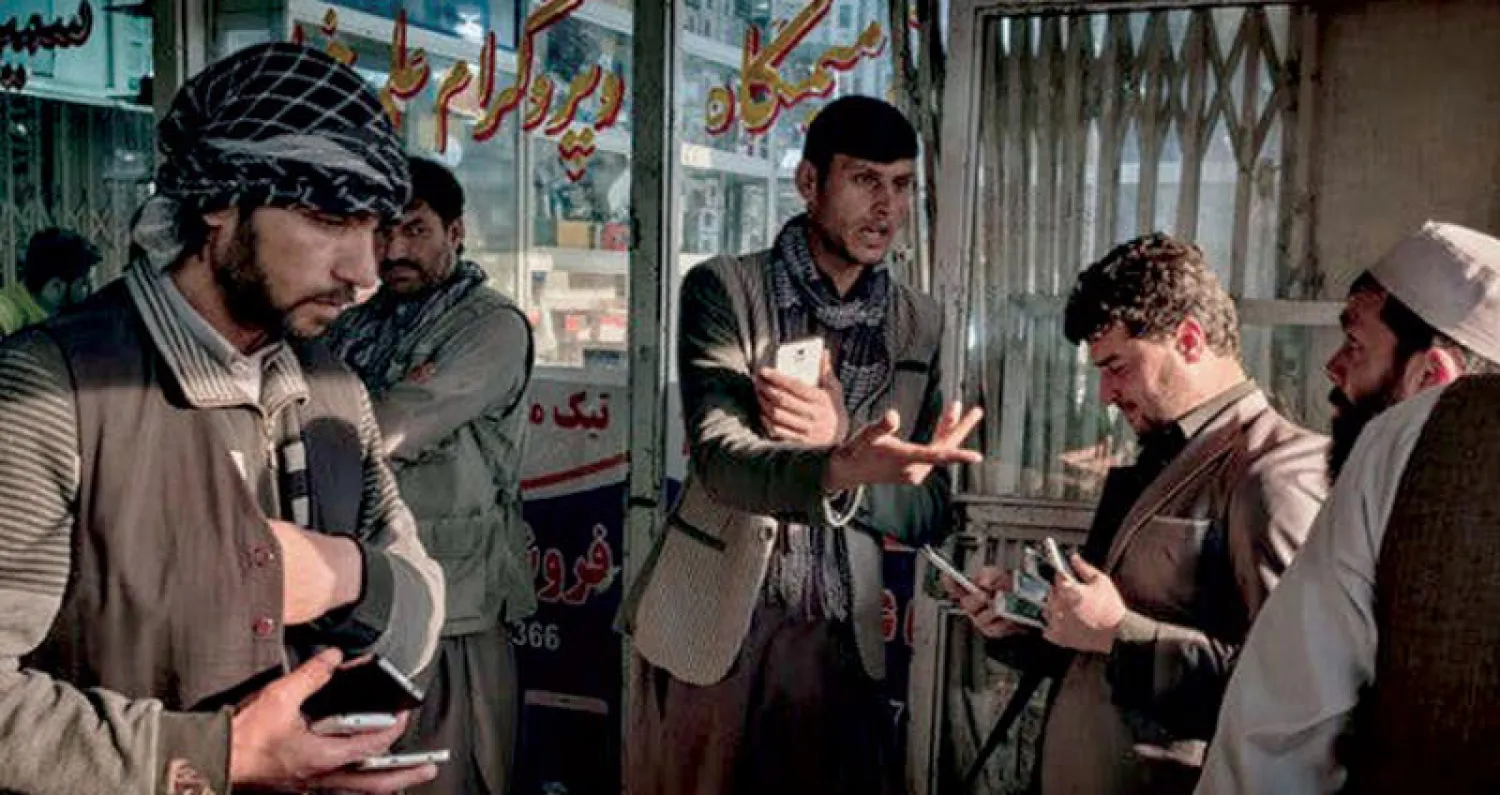 مواطنون أفغان يبيعون ويشترون هواتف محمولة في سوق كابل وسط العاصمة الأفغانية (نيويورك تايمز)