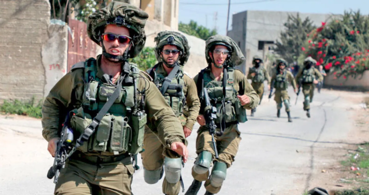 جنود إسرائيليون يلاحقون متظاهرين فلسطينيين أمس ضمن حملة مظاهرات الجمعة ضد مصادرة الأراضي الفلسطينية (أ.ف.ب)