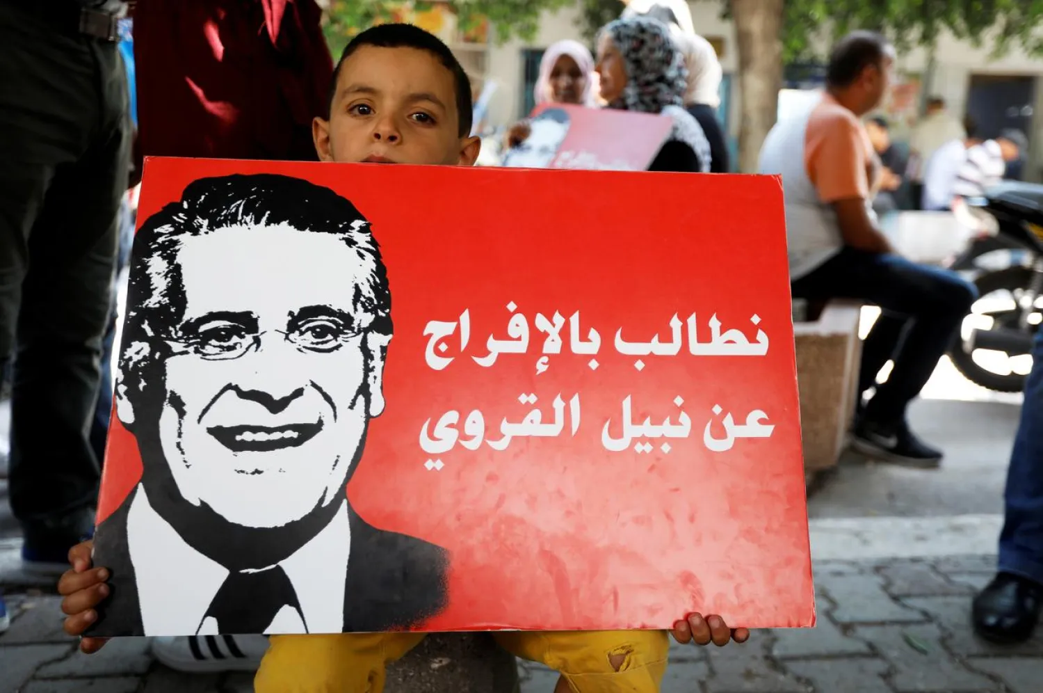 A boy holds a picture of presidential candidate Nabil Karoui as he takes part in a rally to demand his release from prion in front of the courthouse in Tunis, Tunisia, September 3, 2019. (Reuters)