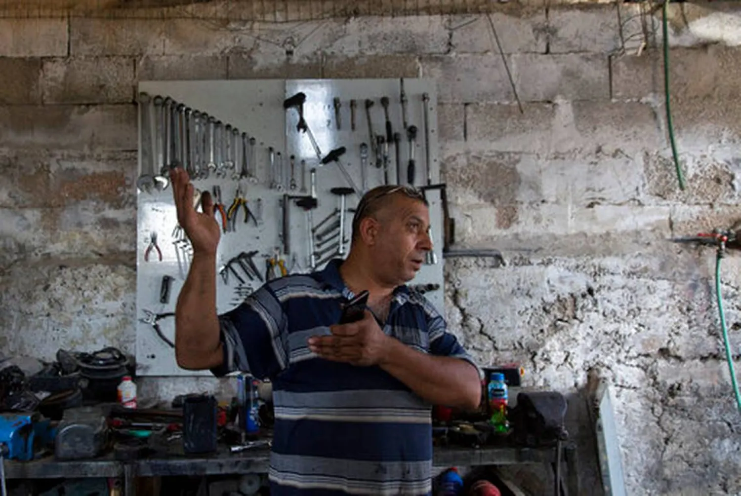In this Wednesday, Sept. 11, 2019 photo, Palestinian Barhoum Saleh gives an interview at his roadside mechanic shop, near the West Bank Israeli settlement of Elkana, west of Qalqiliya. Saleh is among the 2.5 million Palestinians in the West Bank who have no voice in choosing Israel's next government and no control over whether it decides to annex part or all of the occupied territory, as Prime Minister Benjamin Netanyahu has vowed to do. (AP Photo/Nasser Nasser)