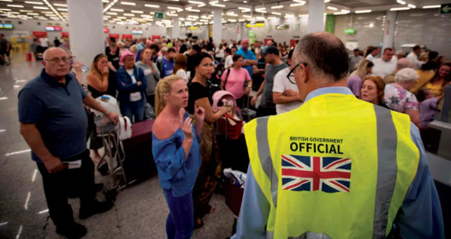 مسؤول بريطاني يتحدث إلى سائحين عالقين جراء إفلاس توماس كوك في مطار بالما دي مايوركا الإسباني (أ.ف.ب)