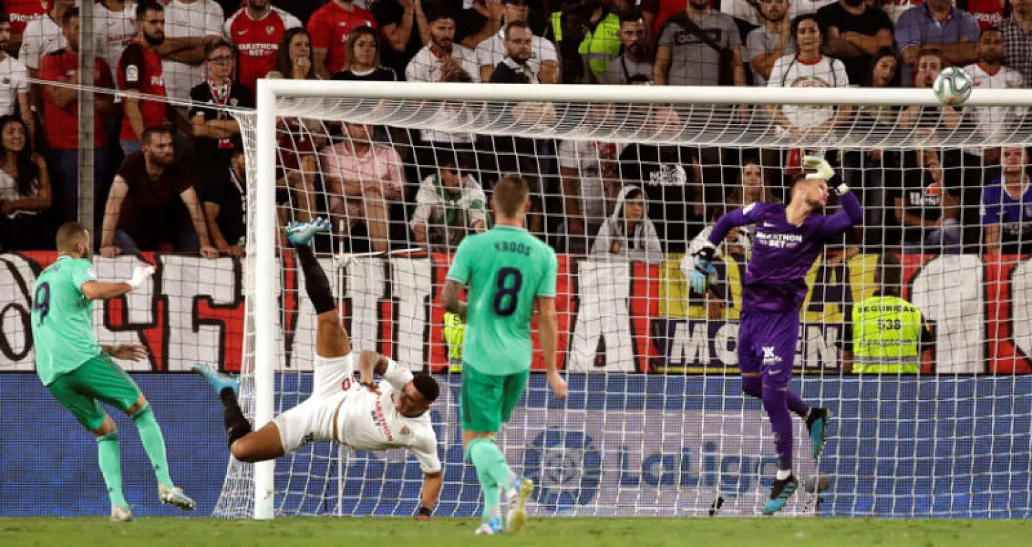 بنزيمة (يسار) يراقب تسديدته الرأسية وهي في طريقها لتسكن شباك إشبيلية لتمنح ريـال مدريد انتصاراً ثميناً (إ.ب.أ)