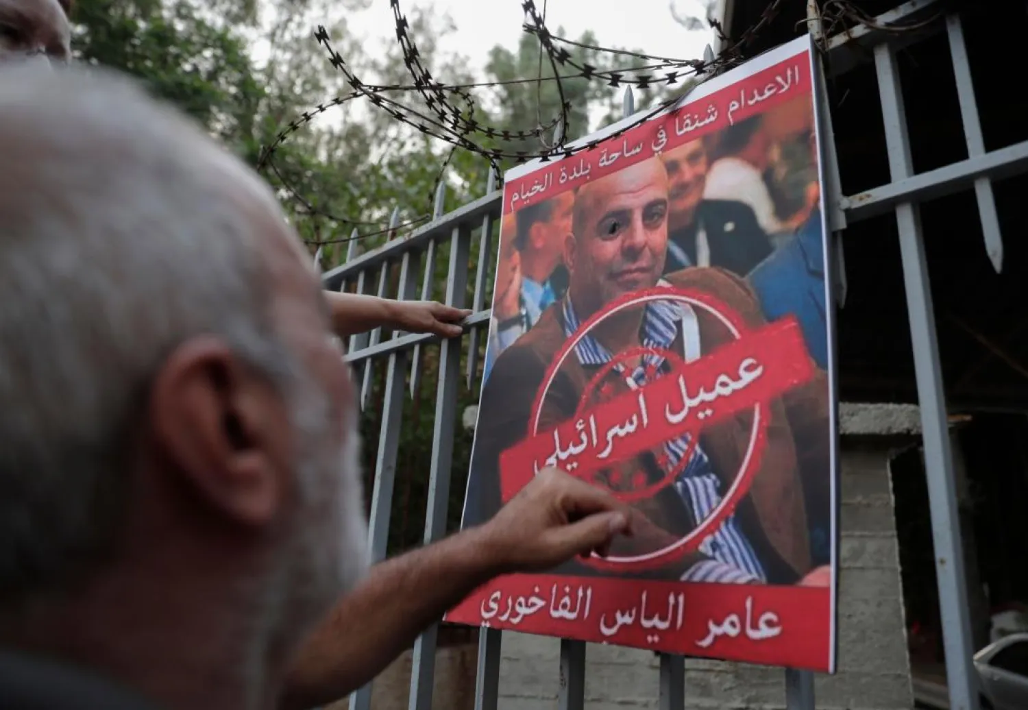 A man formerly detained by the SLA reacts towards a poster depicting former SLA member Amer Fakhoury, during a protest against his return in Beirut on September 12, 2019. (AFP)