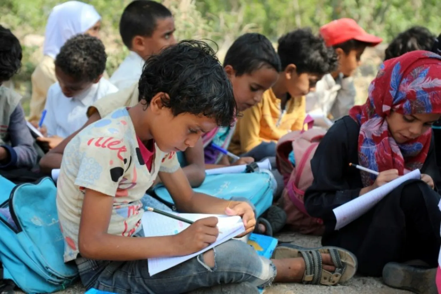 Children attend an open-air class under a tree near their unfinished school on September 16, 2019 in the southwestern Yemeni village of Al-Kashar | AFP