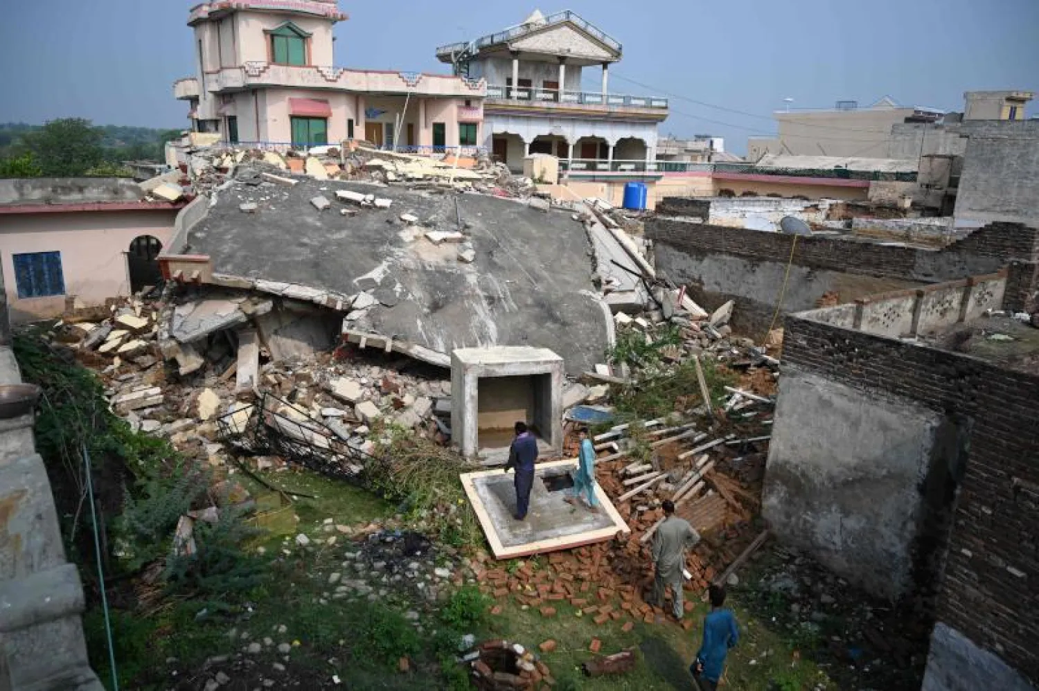 باكستانيون يتفقدون منزلاً مدمراً في منطقة ضربها الزلزال على مشارف ميربور في كشمير (أ.ف.ب)