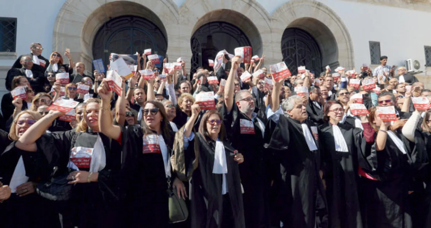 محامون تونسيون يتظاهرون تضامناً مع زملاء لهم يمثلون عائلتي شكري بلعيد ومحمد البراهمي اللذين يُتهم أعضاء جناح سري مرتبط بحركة {النهضة} بالتورط في اغتيالهما قبل سنوات (إ.ب.أ)