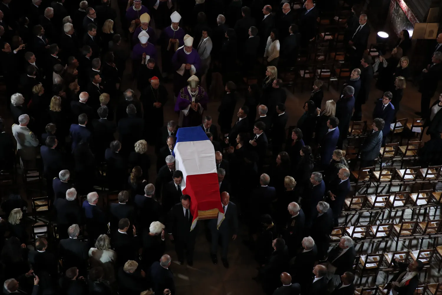 نعش الرئيس الفرنسي الأسبق جاك شيراك محمولاً على الأكتاف لحظة دخوله إلى كنيسة سان سولبيس (أ.ب)