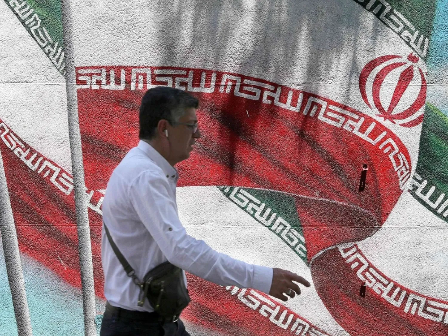 An Iranian man walks past a mural painted with the Iranian flag in Tehran on June 25, 2019. (Getty Images)