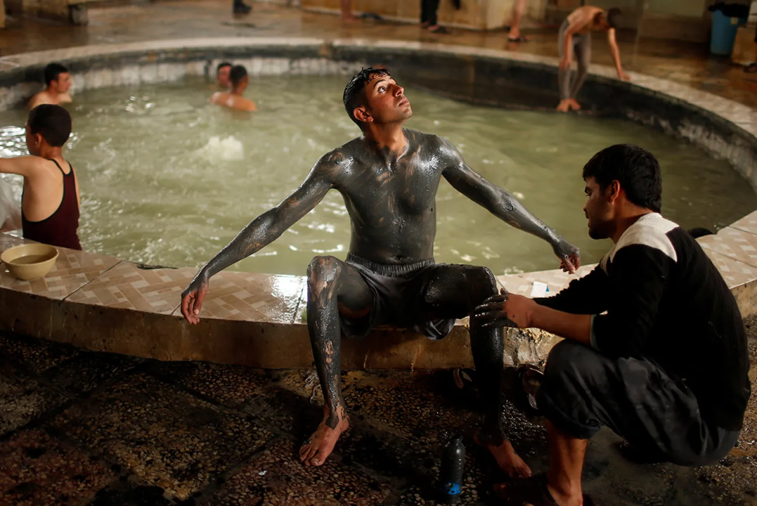 An Iraqi cover his boy with sand from a sulfur pond at Hammam al-Alil city south of Mosul, Iraq April 3, 2017. (Reuters)