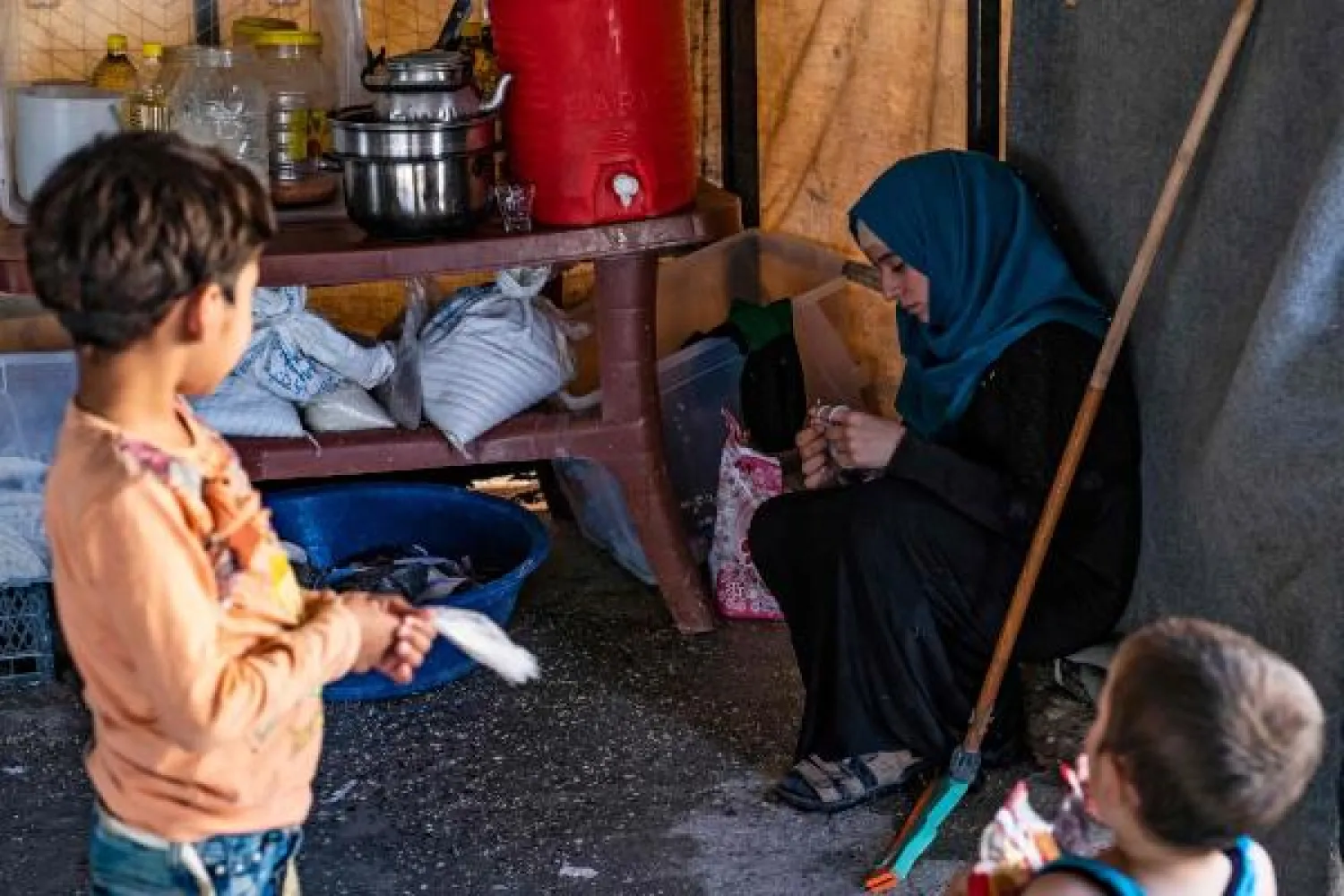 A volunteer caring for 24 orphaned children reportedly linked with foreign fighters of ISIS, knits a garment while children watch at a camp in the northern Syrian village of Ain Issa, on September 26, 2019. (Photo by Delil SOULEIMAN / AFP)
