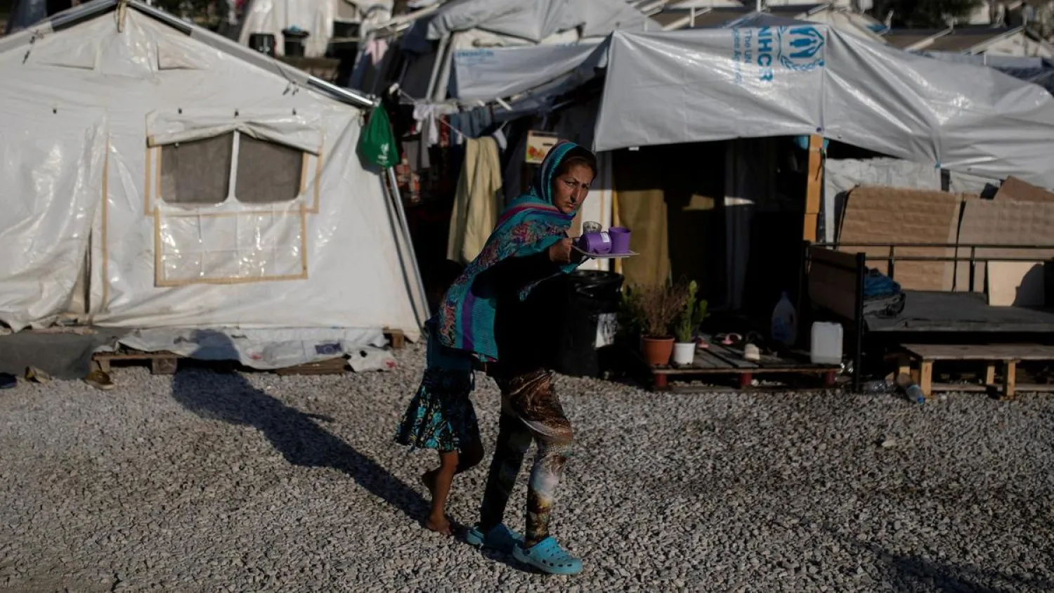 A migrant from Afghanistan and her daughter make their way at a makeshift camp for refugees and migrants next to the Moria camp on the island of Lesbos, Greece. (Reuters)