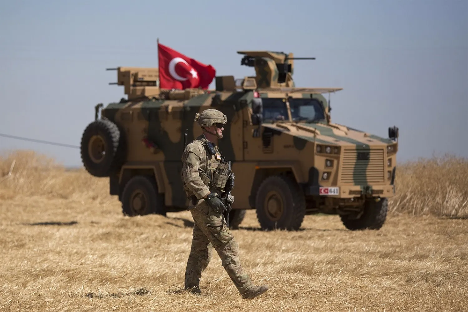 A US soldier walks previous a Turkish armored automobile close to the Syrian border. (AP)