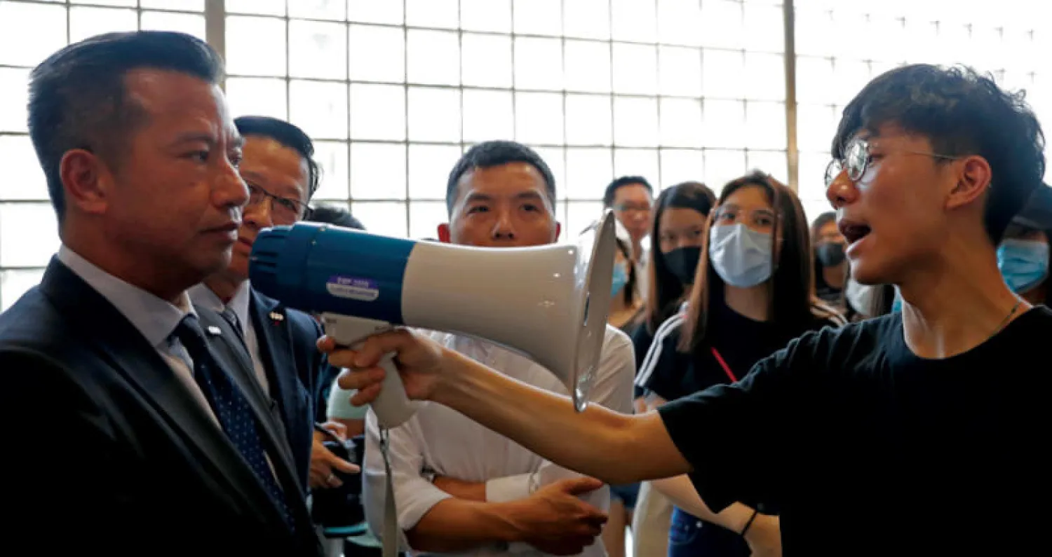 طالب في جامعة هونغ كونغ يواجه أحد المسؤولين بعد دخول الشرطة الحرم الجامعي أمس (رويترز)