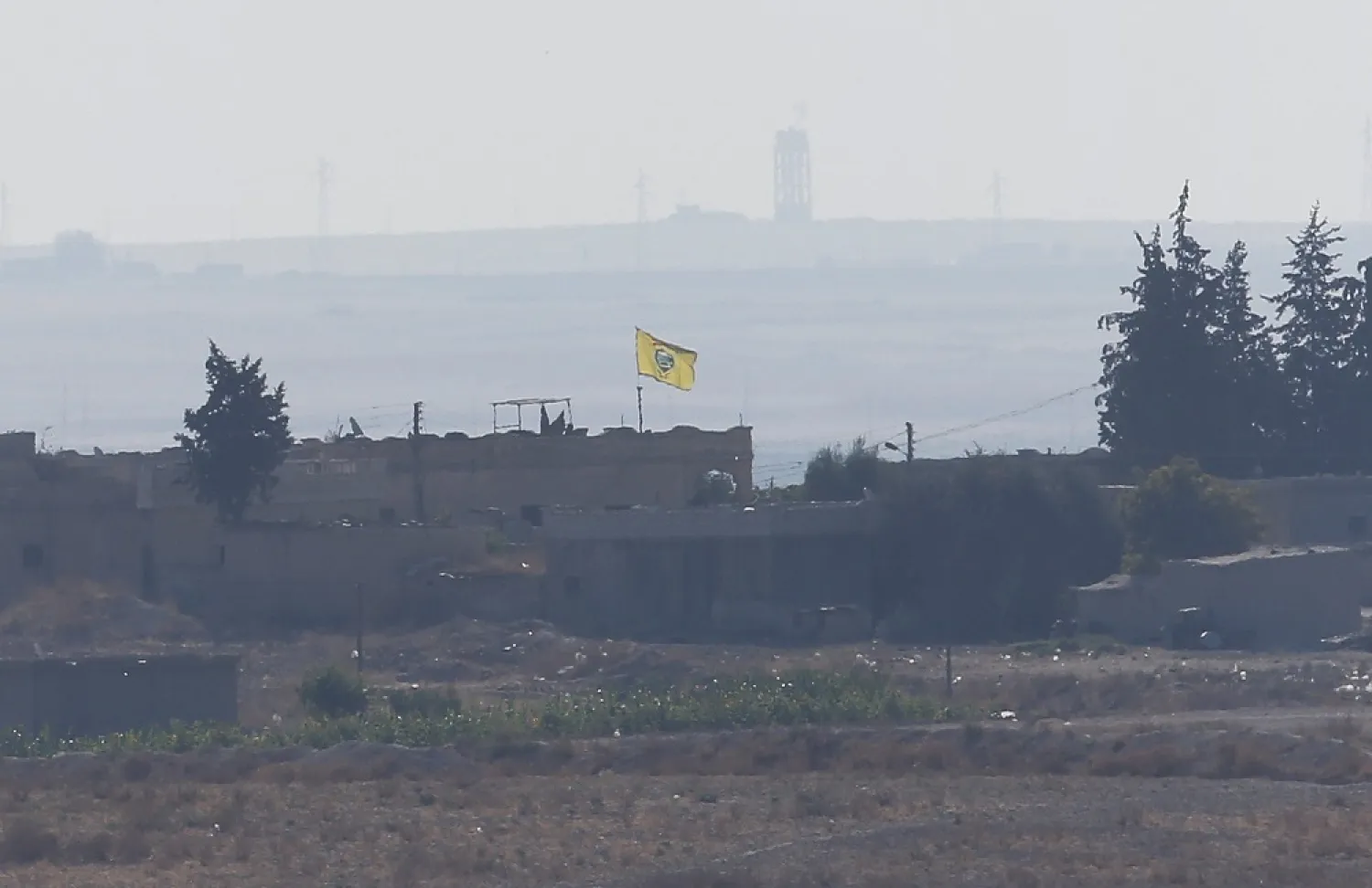 A flag of Kurdish People's Protection Units flies on a building in the Syrian town of Tel Abyad, Tuesday, Oct. 8, 2019. (AP)