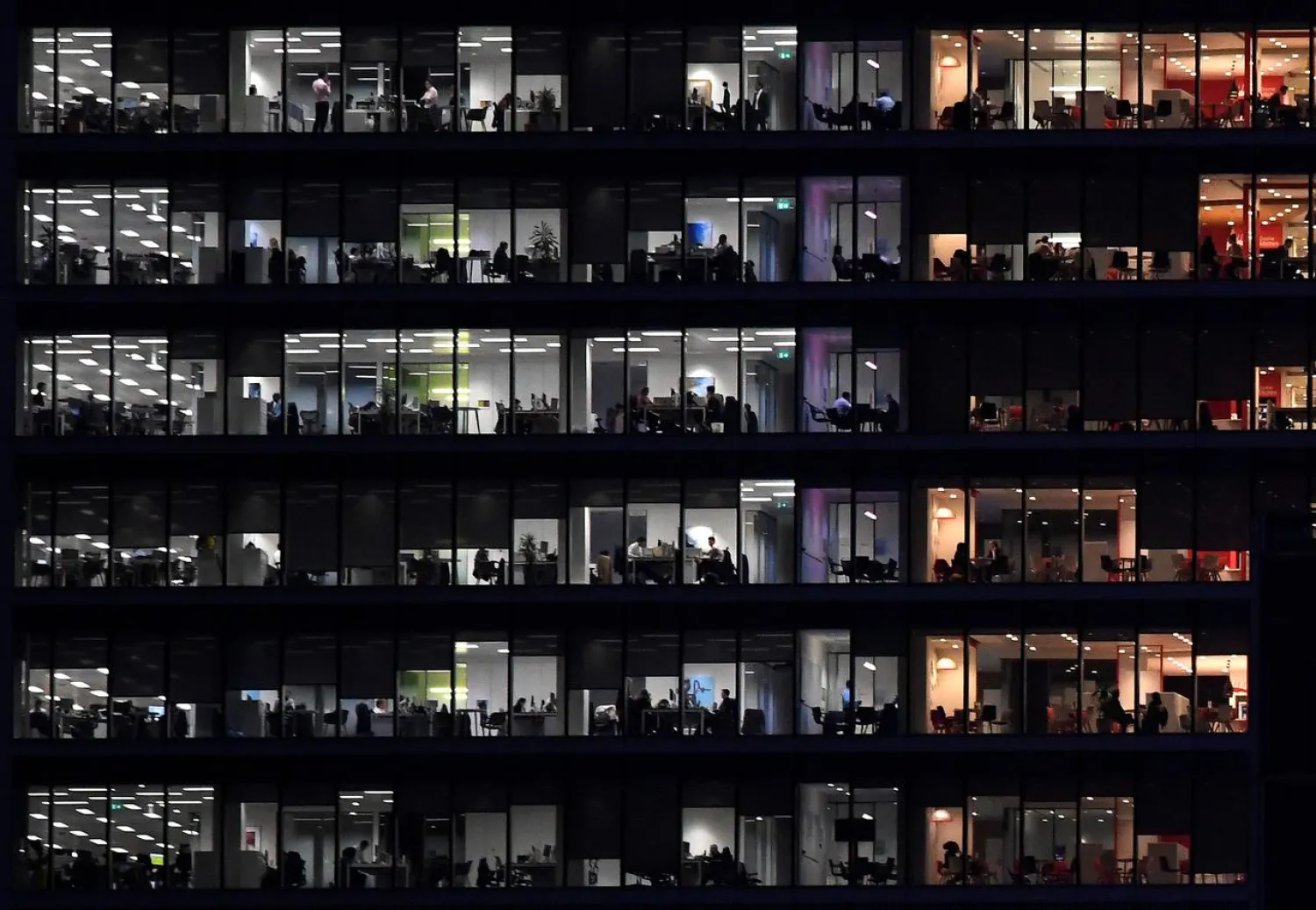 Workers are seen in an office tower in the Canary Wharf financial district at dusk in London, Britain, November 17, 2017. (Reuters)