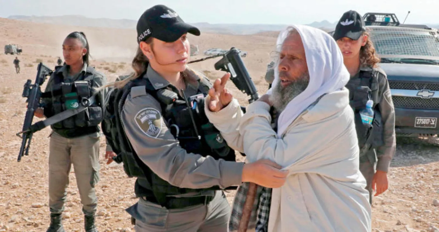 فلسطيني يحاول منع القوات الإسرائيلية من هدم المنازل في بلدة يطّا جنوب الخليل أمس (أ.ف.ب)‎