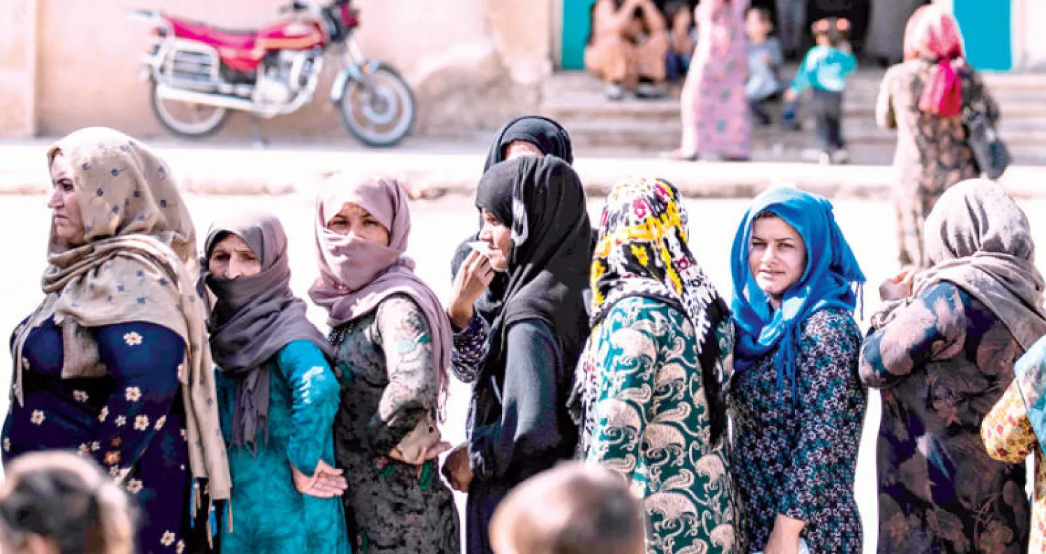 نساء هربن من معارك رأس العين ينتظرن الحصول على مساعدات في بلدة تل تمر شمال شرقي سوريا أمس (أ.ف.ب)