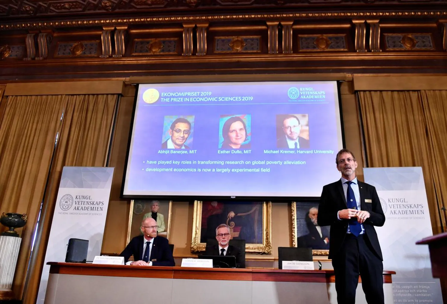 Goran K Hansson, Secretary-General of the Royal Swedish Academy of Sciences, center, and academy members Peter Fredriksson, left, and Jakob Svensson announce the winners of the 2019 Nobel Prize in Economics during a news conference at the Royal Swedish Academy of Sciences in Stockholm, Sweden, Monday Oct. 14, 2019. The Nobel prize in economics has been awarded to Abhijit Banerjee, Esther Duflo and Michael Kremer "for their experimental approach to alleviating global poverty." (Karin Wesslen/TT via AP)