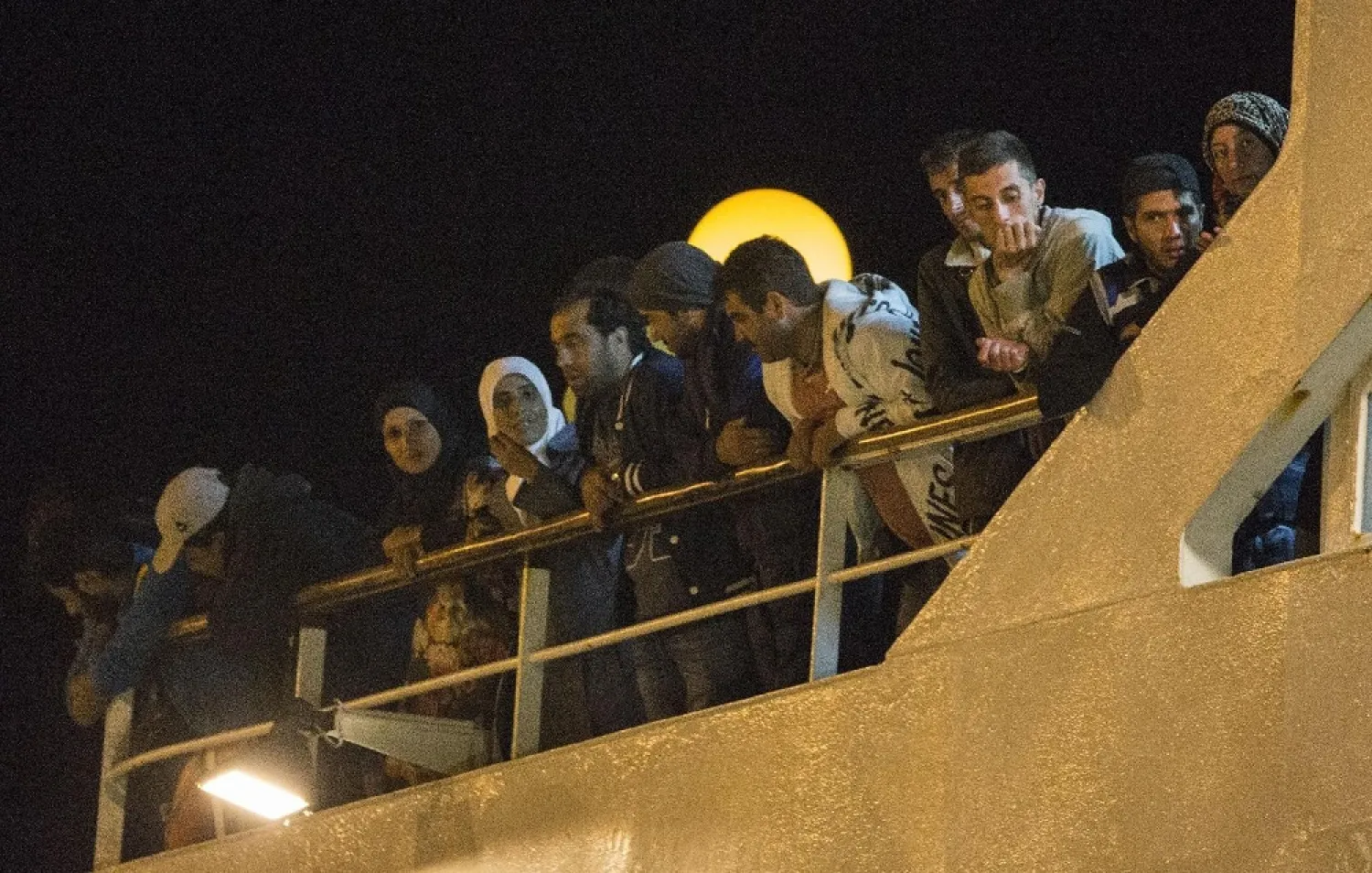 Refugees who were rescued off the coast of Cyprus line the side of a ship at the port in Limassol on September 25, 2014. (AFP)