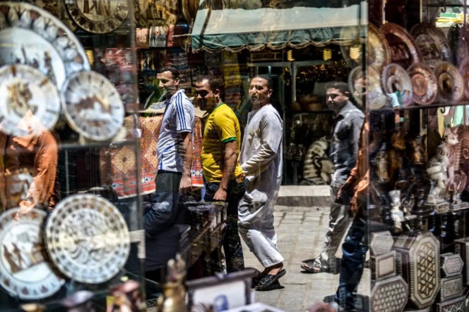 The reflection of Egyptians walking is seen in a shop window at the Khan al-Khalili market in Cairo on May 20, 2016. (AFP)