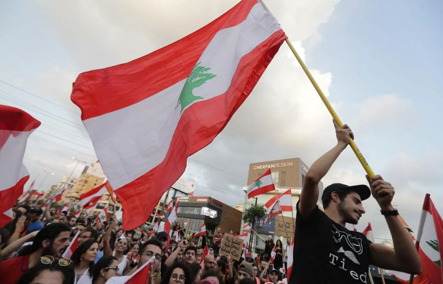 Lebanese demonstrators wave national flags on a highway linking Beirut to north Lebanon, in Zouk Mikael on October 19, 2019. (AFP)