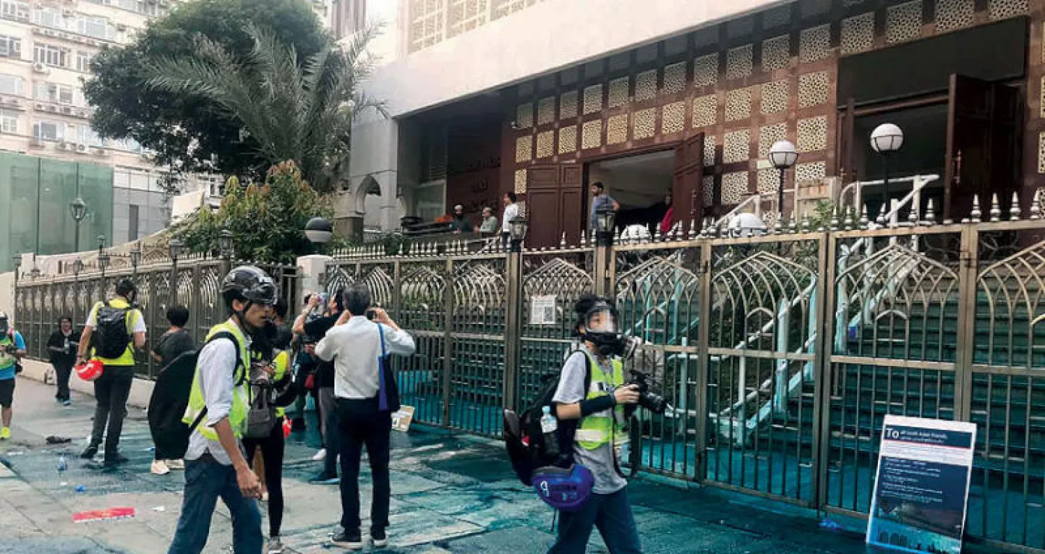 صحافيون يتفقدون مدخل مسجد كولوون الذي تلطّخ بمياه زرقاء في هونغ كونغ أول من أمس (رويترز)
