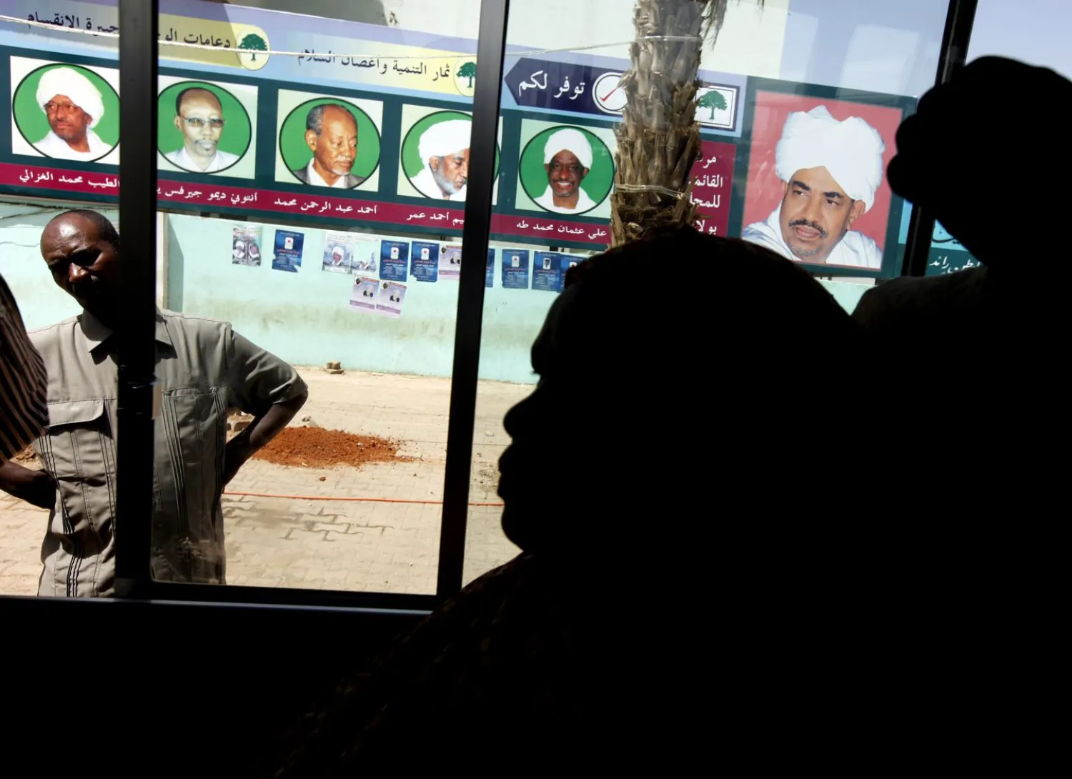 FILE - In this April 10, 2010 file photo, Sudanese women looks through a bus window as it passes posters supporting then Sudanese President and presidential candidate Omar al-Bashir, right, and his ruling National Congress Party candidates, in Khartoum, Sudan. - AP