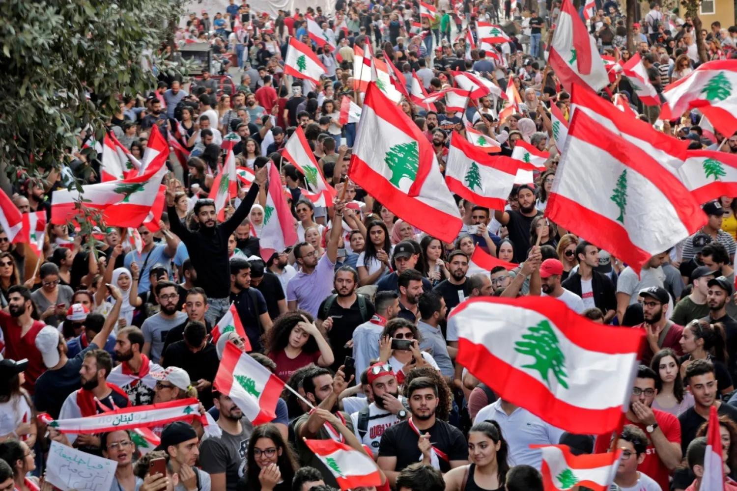 Lebanese protesters wave national flags during demonstrations to demand better living conditions and the ouster of a cast of politicians on October 21, 2019, in downtown Beirut. (Getty Images)
