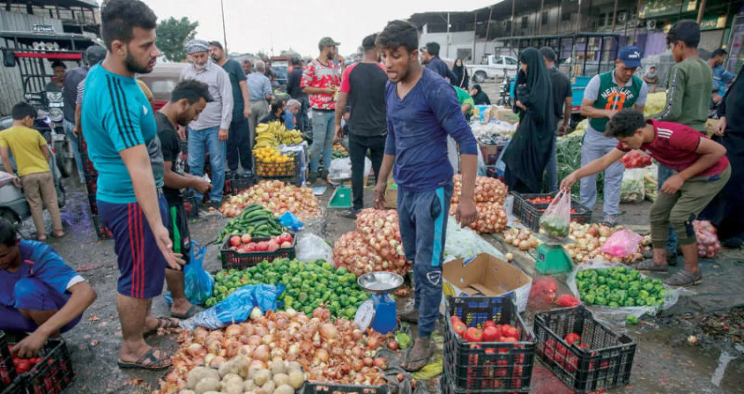 عراقيون يتبضعون في إحدى أسواق شرق بغداد استعداداً للاحتجاجات اليوم (أ.ف.ب)