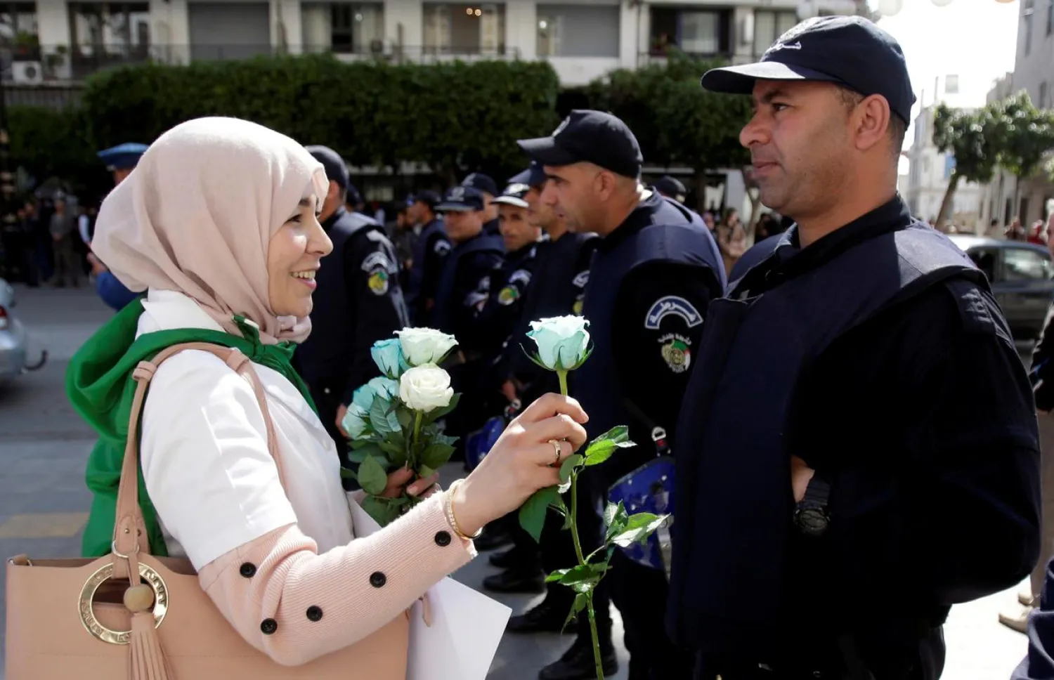A demonstrator offers a flower to a police officer as teachers and students take part in a protest demanding immediate political change in Algiers, Algeria March 13, 2019. REUTERS/Ramzi Boudina