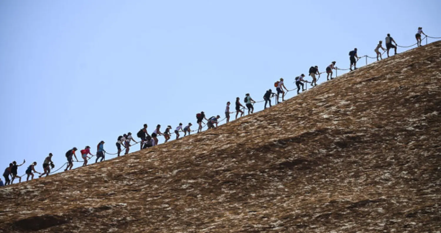 تدفق عشرات من هواة التسلق إلى الجبل الواقع في محمية أولورو كاتا تجوتا في شمال أستراليا قبل يوم من تنفيذ الحظر (إ.ب.أ)