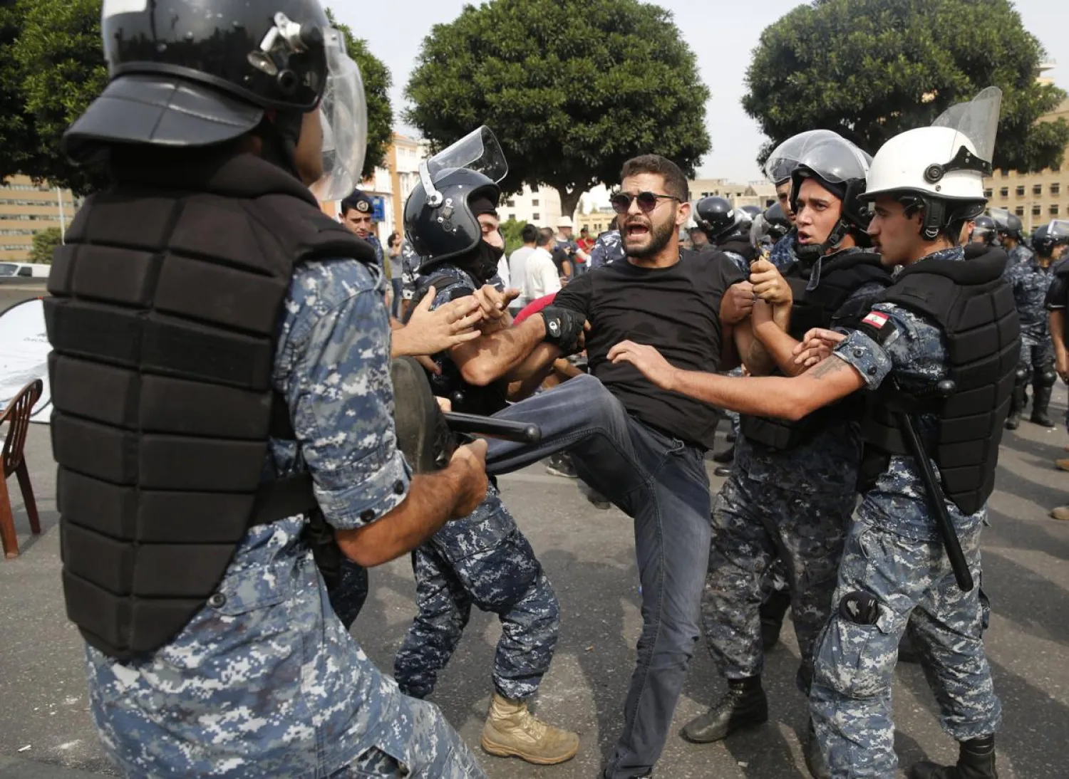 Police remove an anti-government protester blocking a main highway with his body in Beirut, Lebanon, Saturday, Oct. 26, 2019. The removal of the roadblocks on Saturday comes on the tenth day of protests in which protesters have called for civil disobedience until the government steps down. (AP Photo/Hussein Malla)