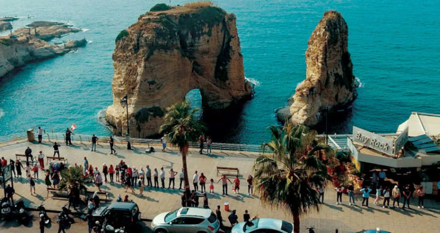 مشاركون في السلسلة البشرية أمام صخرة الروشة في بيروت أمس (أ.ف.ب)