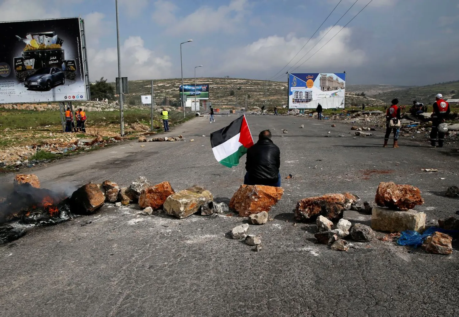 A demonstrator holds a Palestinian flag as he sits during clashes with Israeli troops near the settlement of Beit El, near Ramallah in the occupied West Bank February 23, 2018. (Reuters)