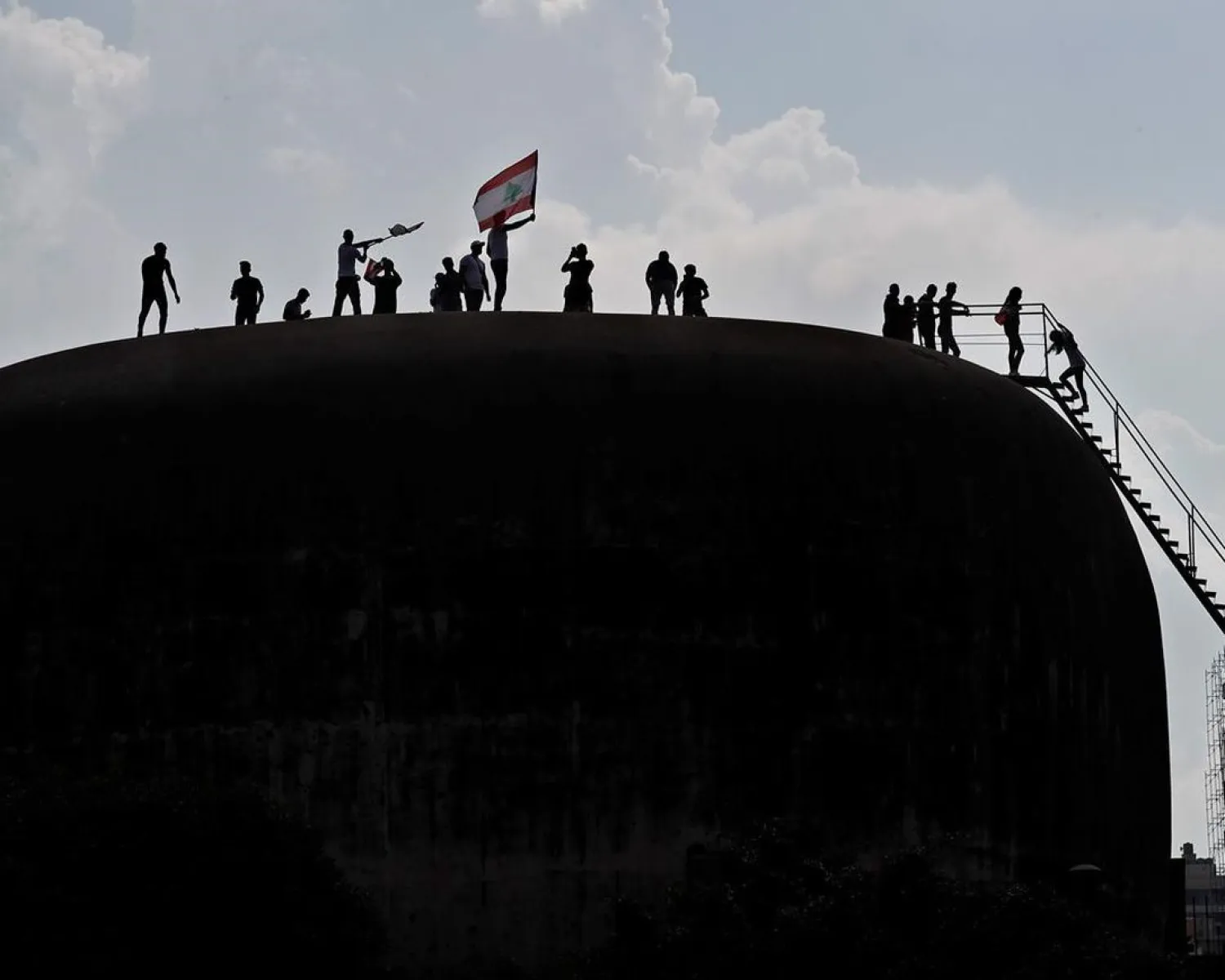 Anti-government protesters wave the Lebanese flag as they stand on the roof of the Dome City Center, known as ‘The Egg’, in Beirut, Lebanon on October 20, 2019. (AP)