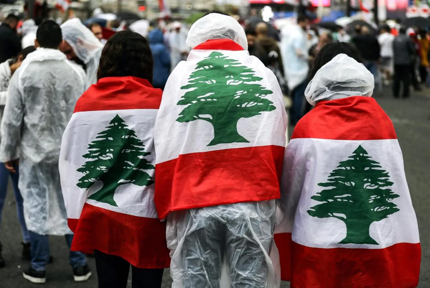 Protesters wearing ponchos and draped with the Lebanese national flag stand under the rain in Zouk Mosbeh, north of the capital Beirut. (AFP)