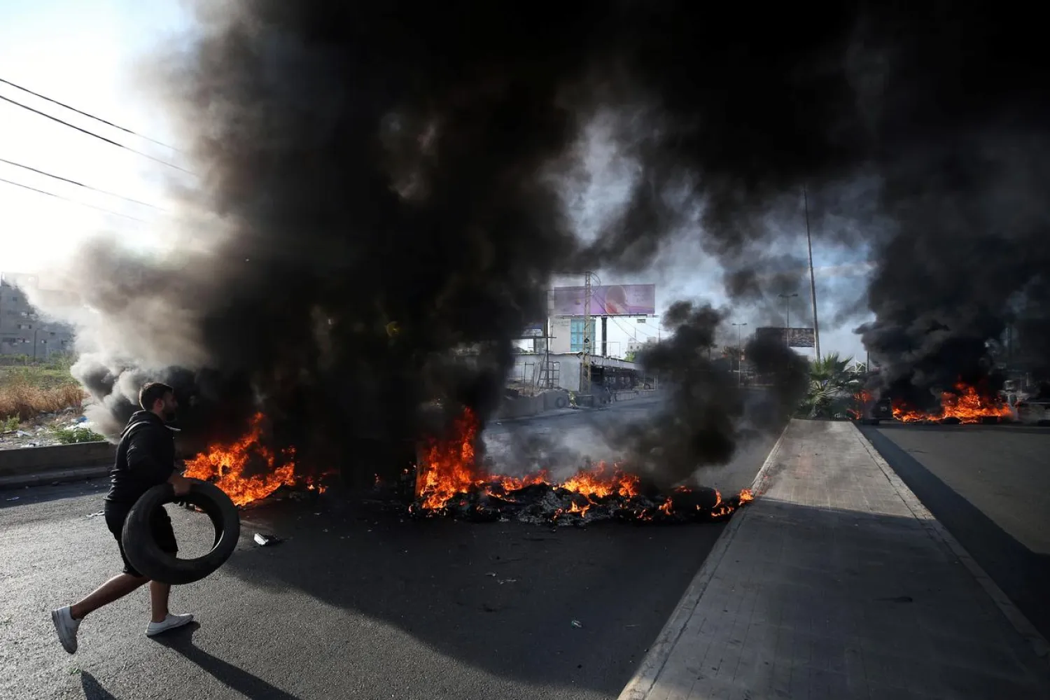 A demonstrator burns tires blocking a road in the port city of Sidon, Lebanon, October 28, 2019. REUTERS/Ali Hashisho