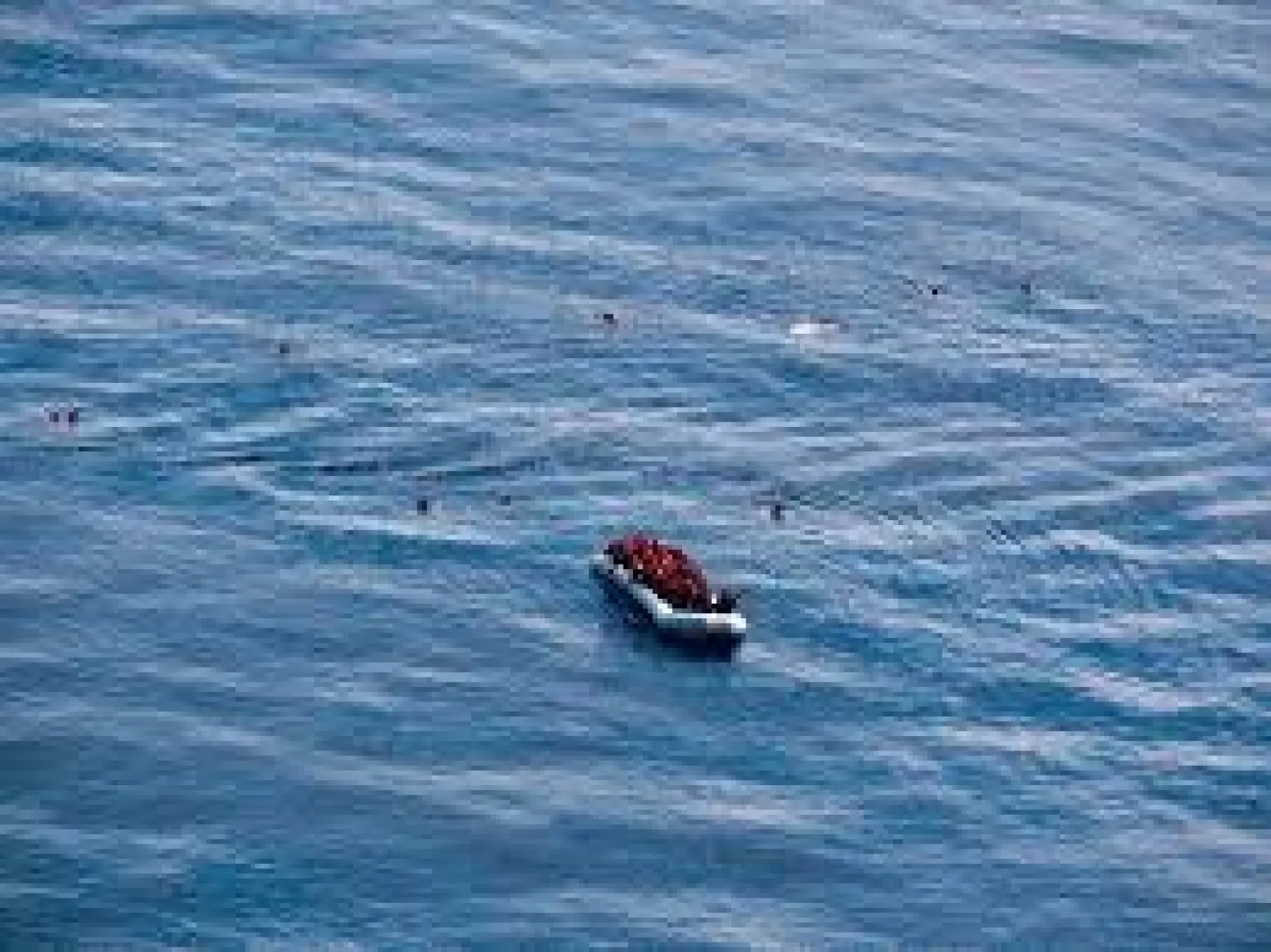 In this photo taken on Saturday, Oct. 26, 2019, an aerial view of migrants on a dinghy boat, some of them in the water, off the coast of Libya. (Sea-Eye via AP)