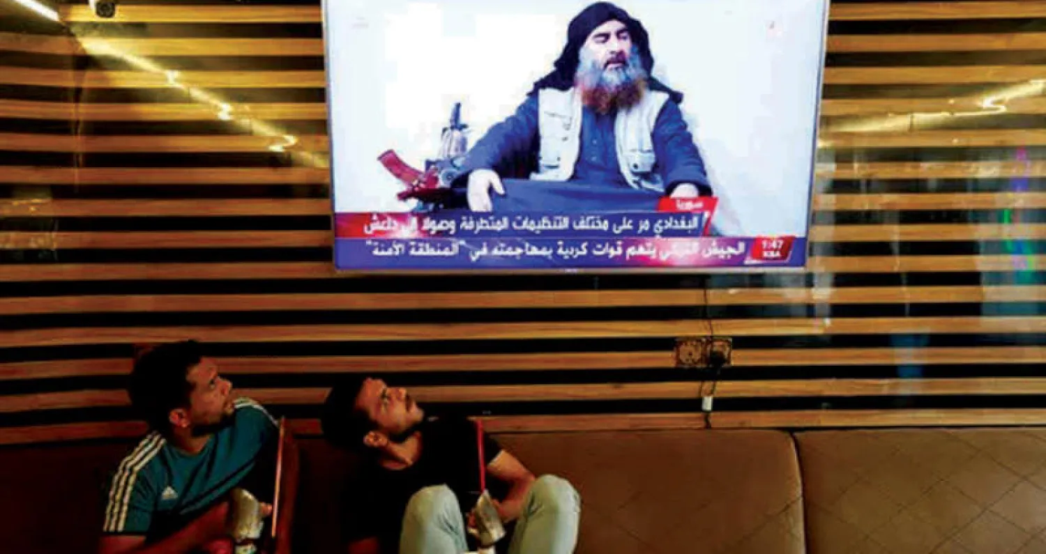 عراقيان يتابعان في مقهى بالنجف تفاصيل إعلان مقتل البغدادي زعيم «داعش» الأحد الماضي (رويترز)