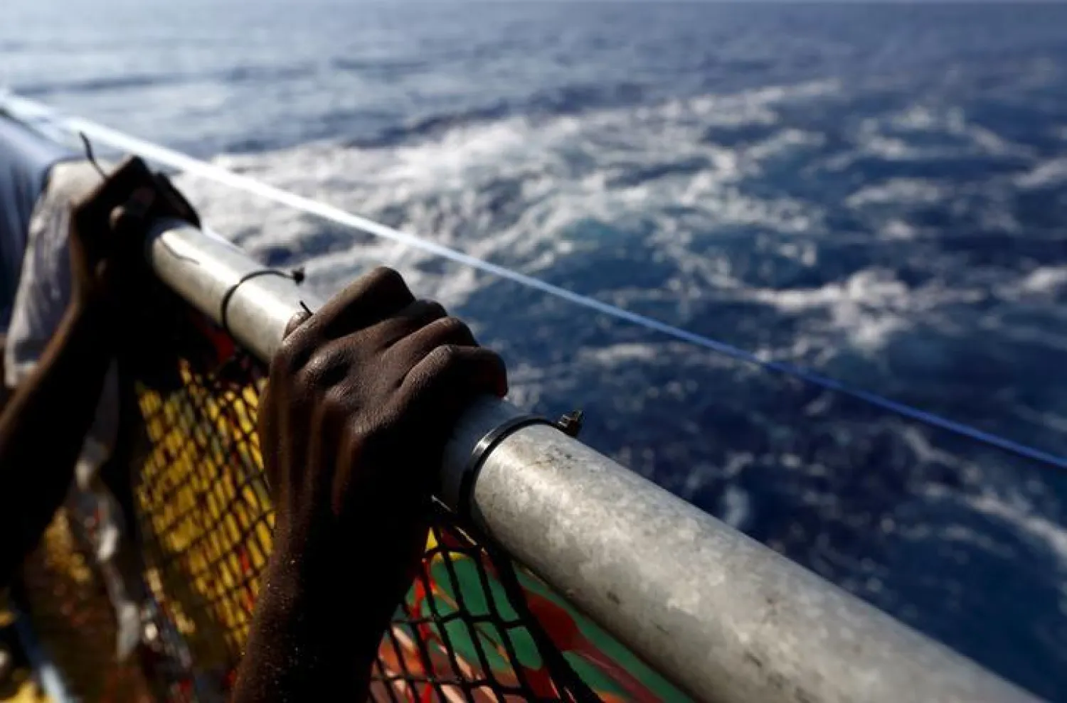 A migrant holds onto a railing at the stern of the Medecins Sans Frontiere (MSF) rescue ship Bourbon Argos somewhere between Libya and Sicily (File Photo: Reuters)