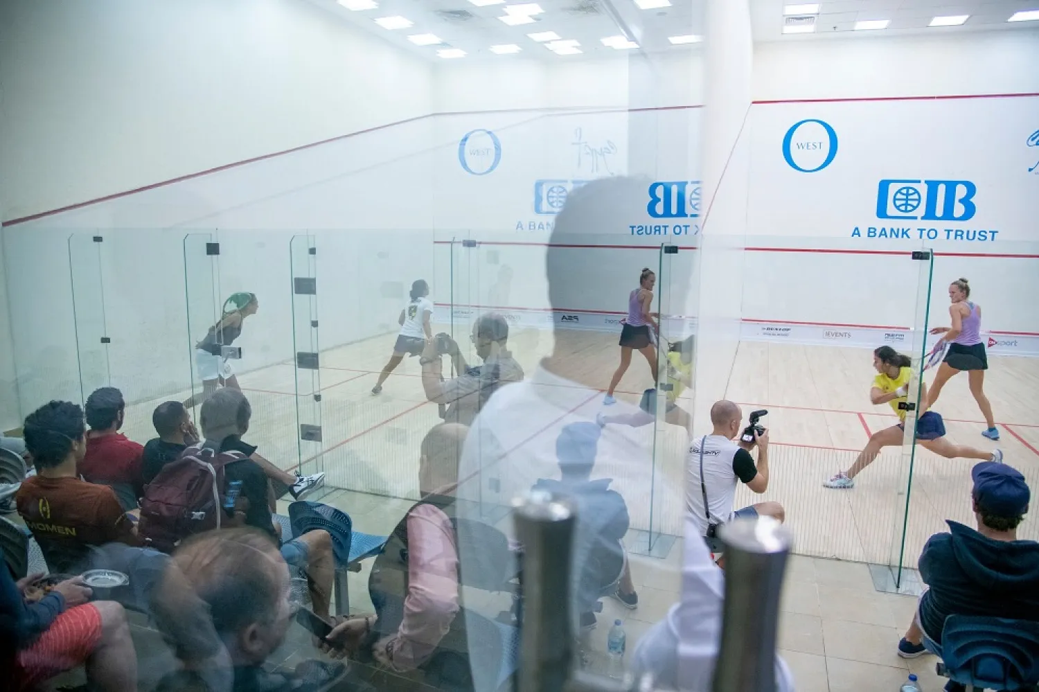Second-ranked Nour El Sherbini, in yellow, played on a court next to El Welily in the first round of the women’s world championship. (The New York Times)