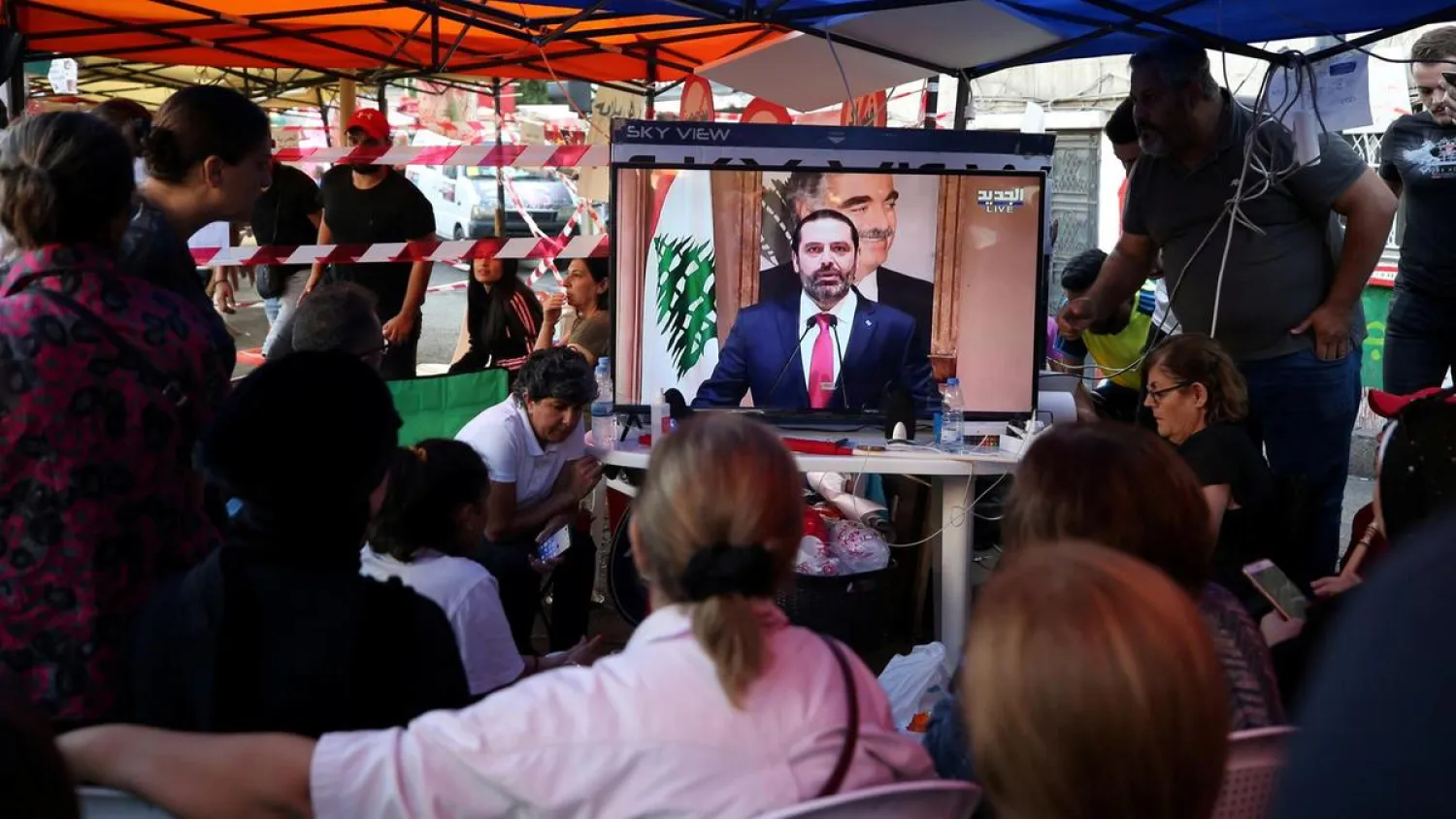 Protestors in south Lebanon’s Sidon watch a television broadcast of Lebanon's Prime Minister Saad Hariri as he announces his resignation. (Reuters)