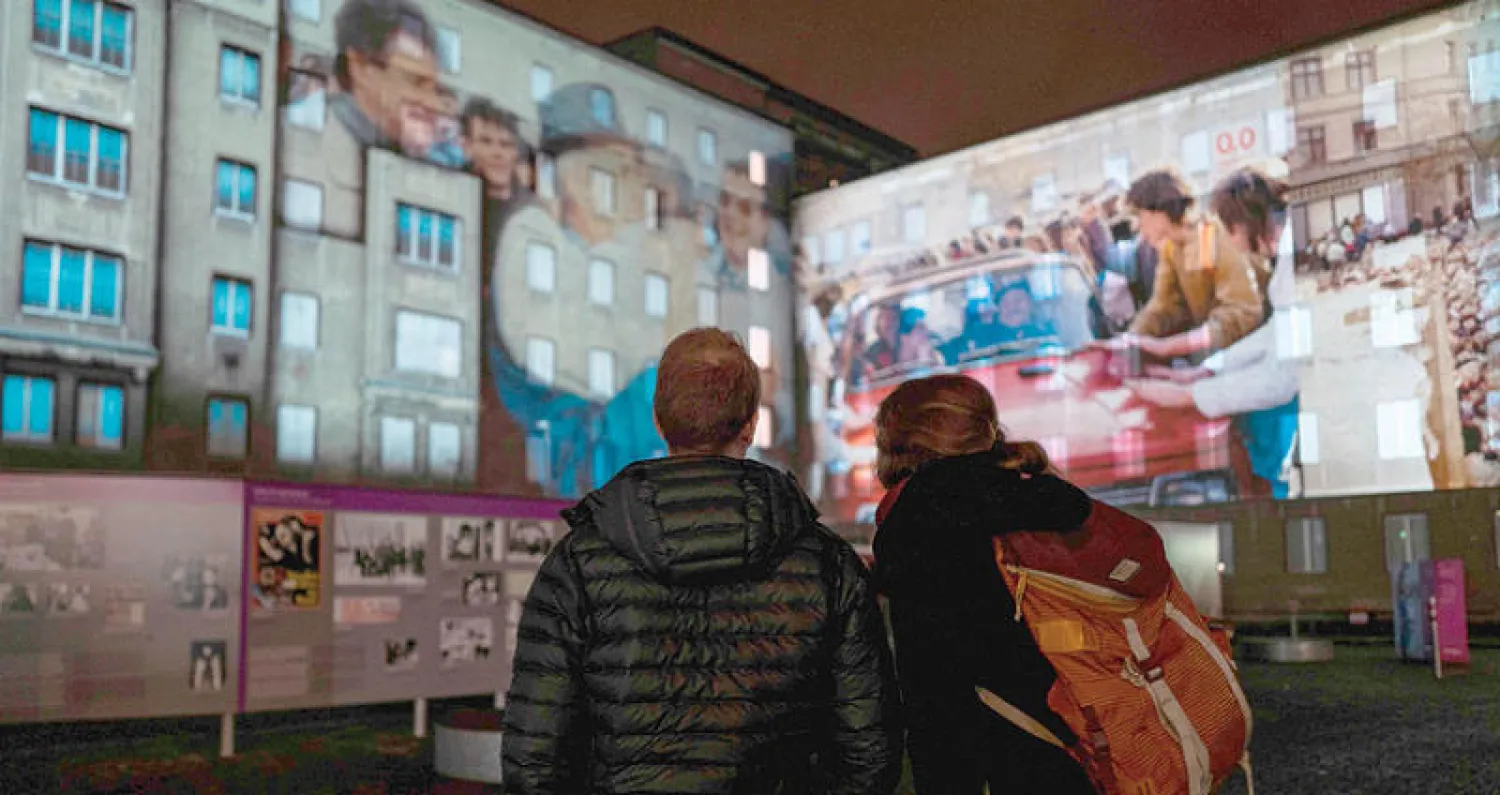 عرض شريط يُظهر ألمانياً يمشي من ألمانيا الشرقية إلى الغربية بعد سقوط الجدار في معرض ببرلين أول من أمس (أ.ف.ب)