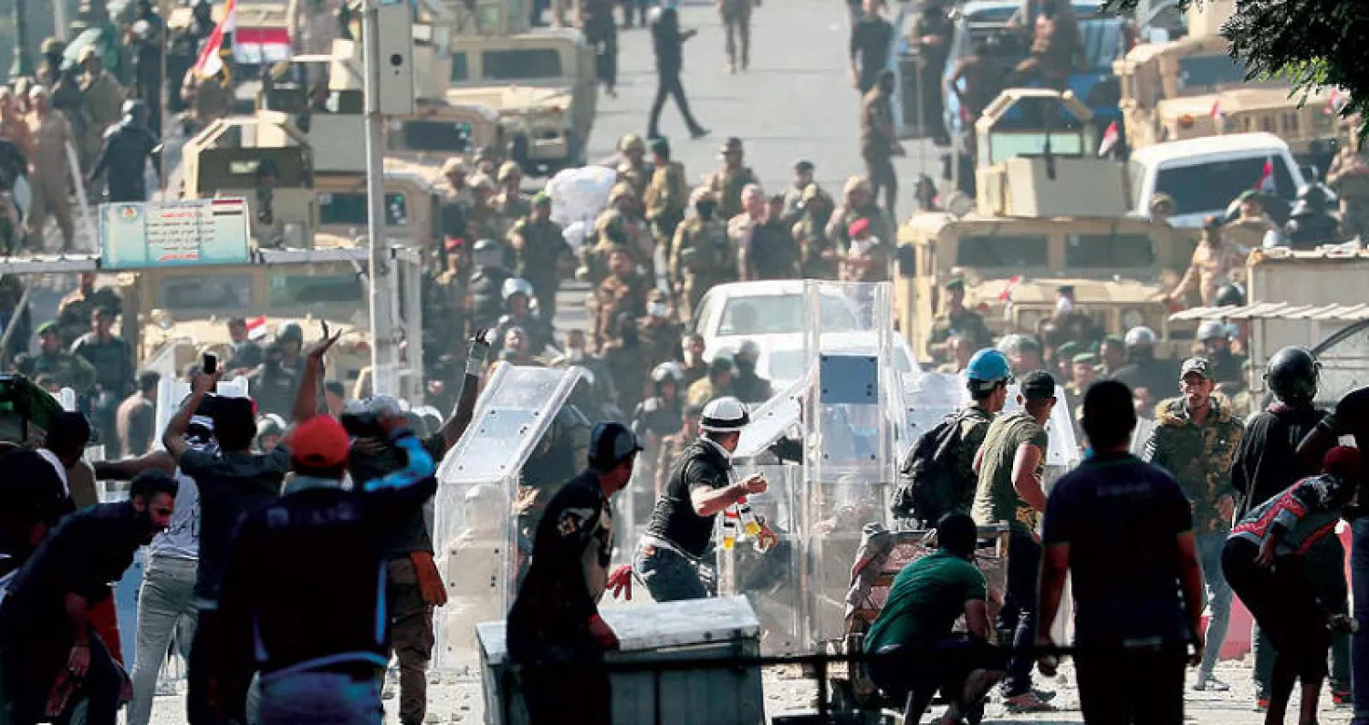 قوات مكافحة الشغب في مواجهة محتجين على جسر الشهداء وسط بغداد أمس (أ.ب)