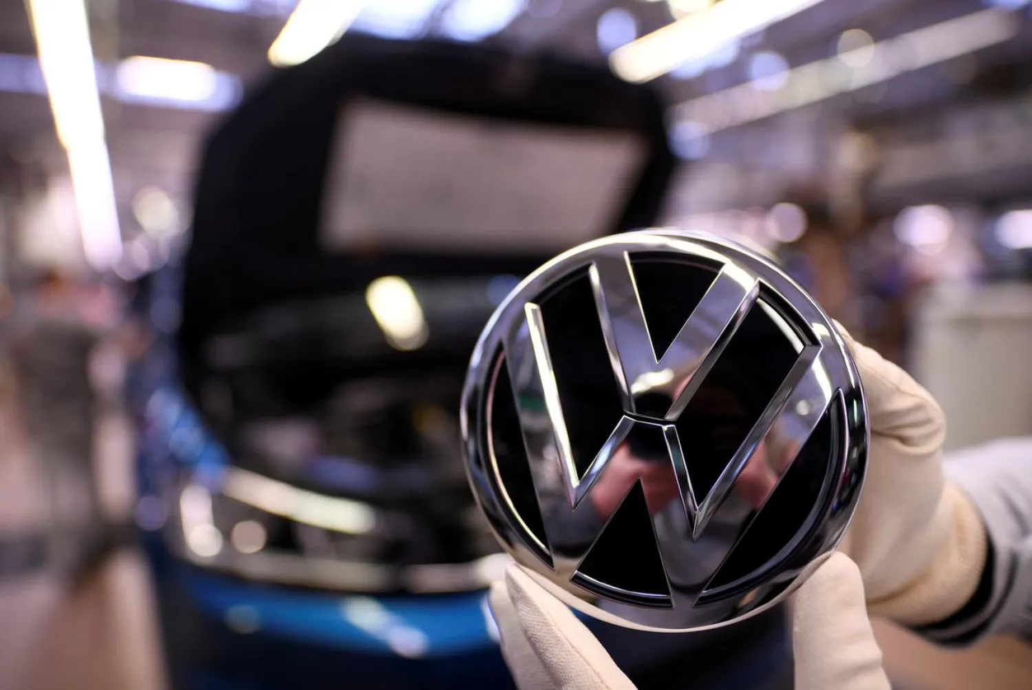 An employee holds a Volkswagen logo in a production line at the Volkswagen plant in Wolfsburg, Germany March 1, 2019. (Reuters)