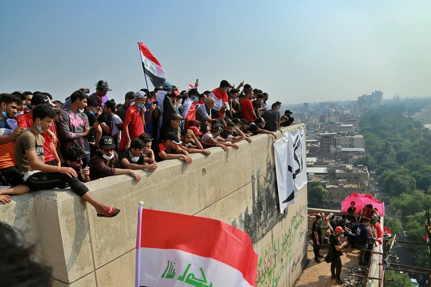 Iraqi anti-government protesters stand on a building near Tahrir Square in Baghdad on Oct. 31, 2019. (AP)