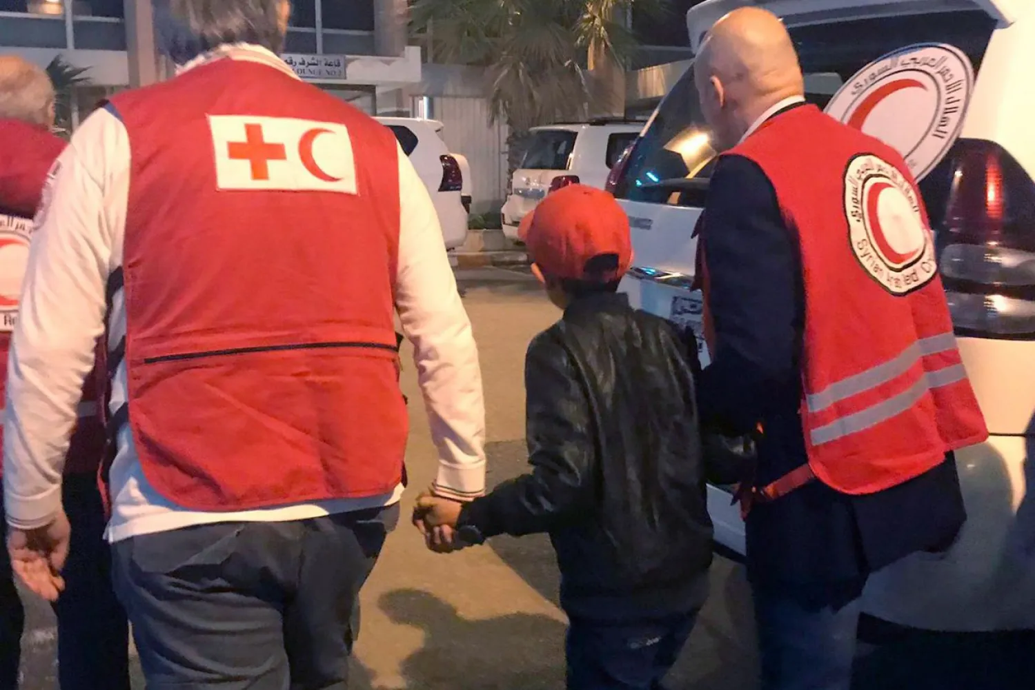 In this Nov. 6, 2019, Alvin, an Albanian boy who was taken to Syria by his mother when she joined the ISIS group, is accompanied to Damascus airport by Red Cross and Red Crescent officials. (AP)